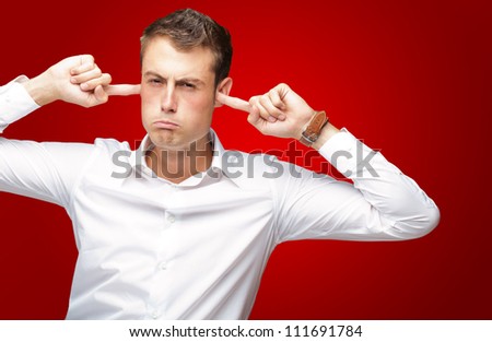 Portrait Of Young Man With Finger In His Ear On Red Background