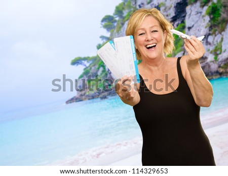 Woman Holding Boarding Pass And Miniature Airplane On Beach
