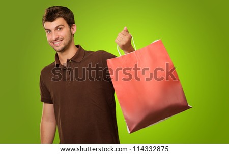 Portrait Of A Young Man Holding Shopping Bag On Green Background