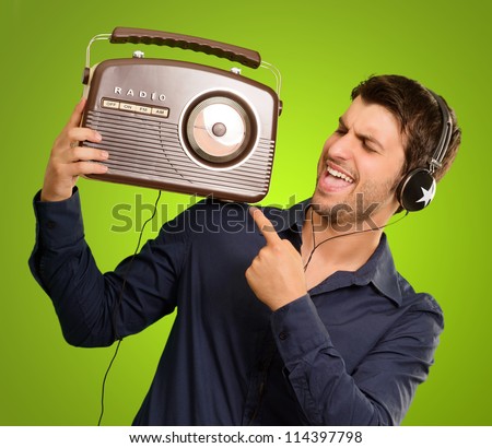 Young Man Listening To Vintage Radio On Green Background - stock photo