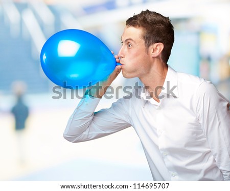 Portrait Of Young Man Blowing And Holding A Balloon