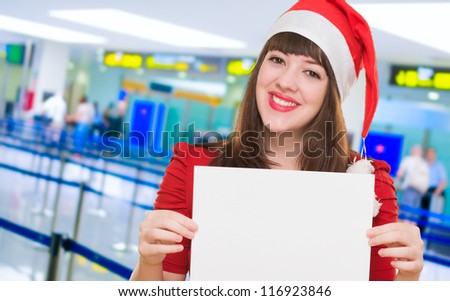 happy christmas woman holding a blank card at the airport