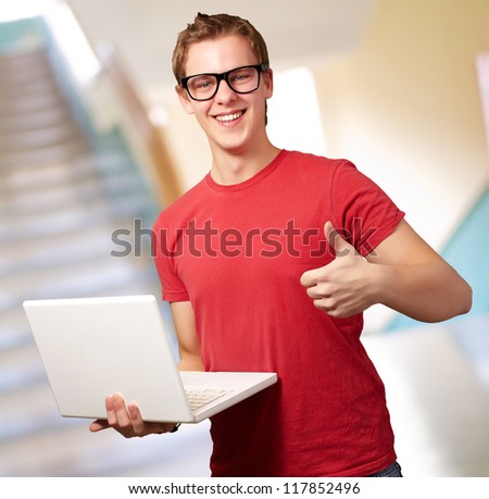 Man holding laptop with thumbs up, indoor
