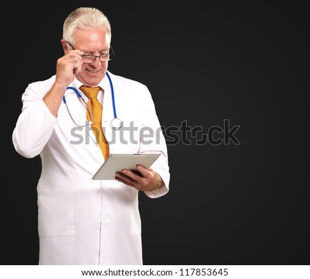 Portrait Of A Male Doctor Holding A Tab On Black Background