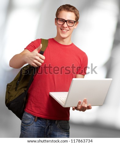 man holding laptop and backpack, indoor