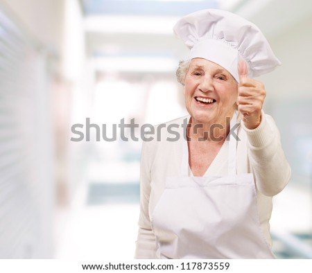 portrait of cook senior woman doing good gesture at restaurant