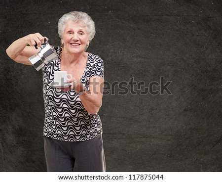portrait of a vitality senior woman serving a tea cup against a grunge wall