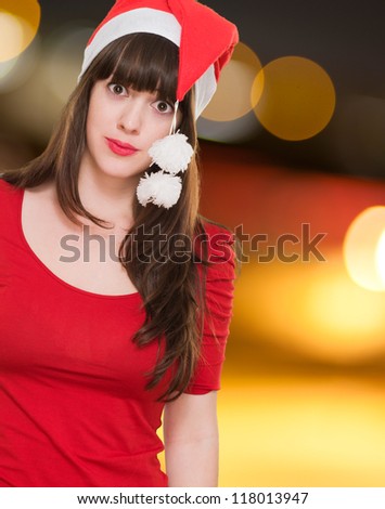 confused woman wearing a christmas hat against a city by night