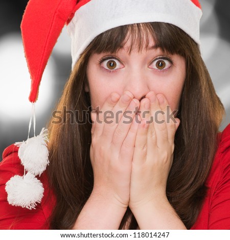 closeup of a surprised christmas woman covering her mouth against a grunge wall