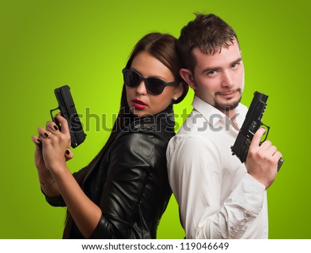 Young Couple Holding Gun against a green background