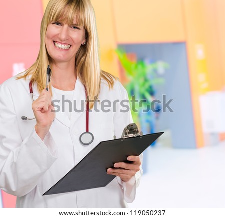 happy female doctor holding a clipboard at the hospitals waiting area