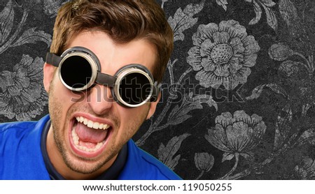 Portrait of an engineer wearing goggle, floral wallpaper