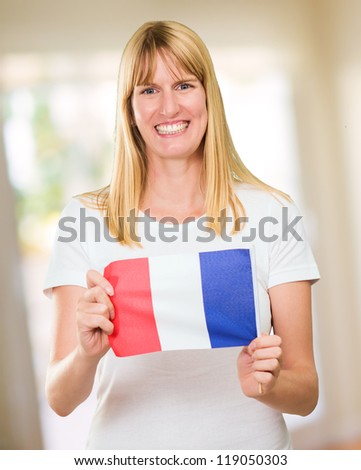 woman holding a french flag against an abstract background, indoor