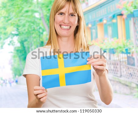 Happy Woman Holding Swedish Flag in front of a restaurant, outdoor