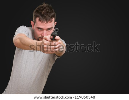 serious man pointing with gun against a black background