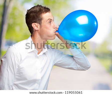 Portrait Of Young Man Blowing A Balloon, Outdoor