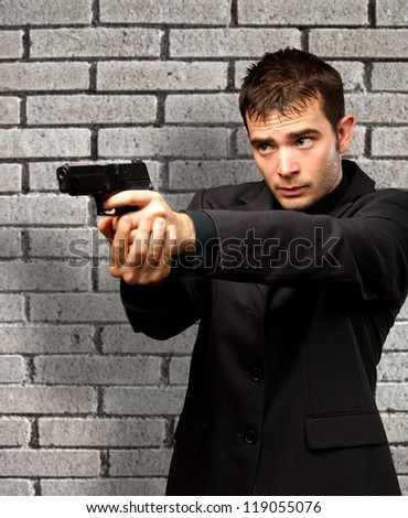 Man Holding Gun against a brick wall background