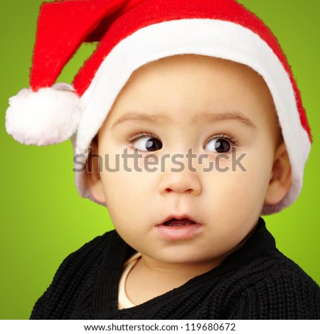 Baby Boy Wearing Santa Hat Holding Christmas Ornaments against a green background