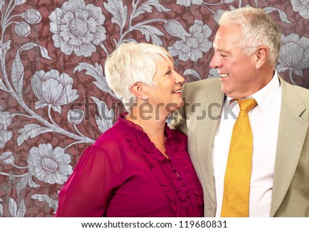 Portrait Of A Happy Senior Couple On Wallpaper Background