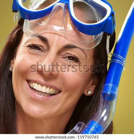 portrait of a happy middle aged woman wearing snorkel and goggles over yellow