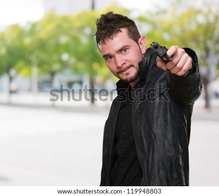 mad man pointing with gun against a street background