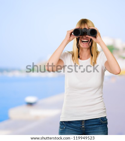 happy woman looking through binoculars at a port