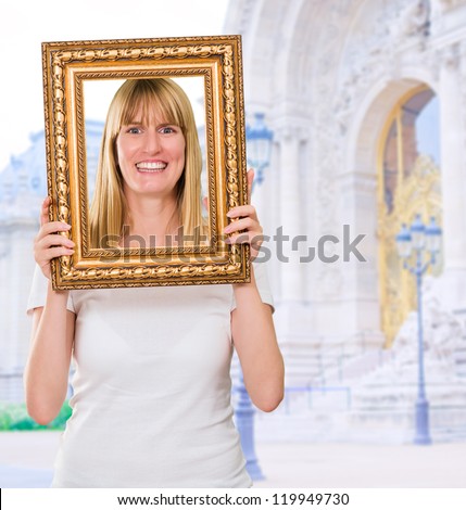 Portrait Of A Happy Woman Holding Frame in front of a building