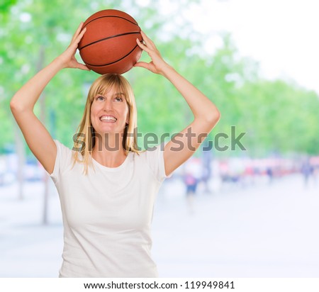 Happy Woman Holding Basket Ball against a street background