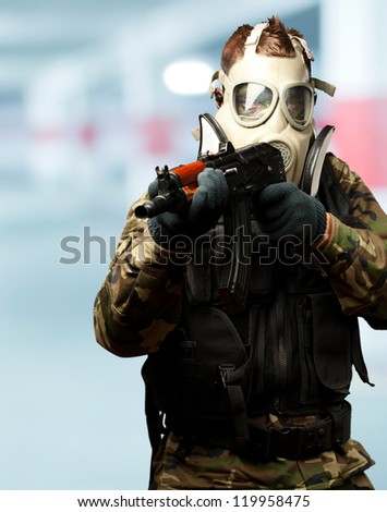 Portrait Of A Soldier With Gas Mask Aiming With Gun in a garage