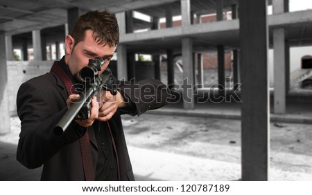 Man in suit pointing with a rifle, indoor