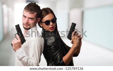 Young Couple Holding Gun against an abstract background