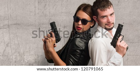 Young Couple Holding Gun against a grunge background