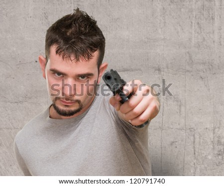 portrait of serious man pointing with a gun against a grunge background