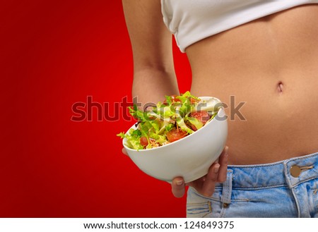 Female Holding A Bowl Of Salad On A Red Background