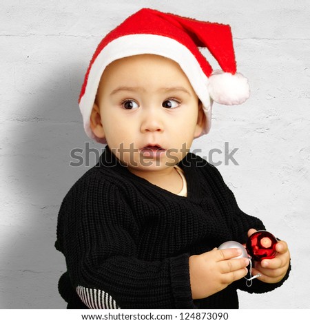 Baby Boy Wearing Santa Hat Holding Christmas Ornaments against a grunge background