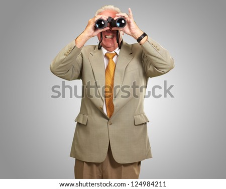 Senior Man Looking Through Binoculars On gray Background