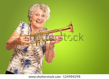 Portrait Of A Senior Woman Holding A Trumpet On Green Background