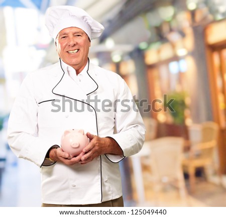 Portrait Of A Chef Holding Piggy Bank, Indoor