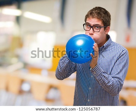 Young Man Blowing Blue Balloon, indoor