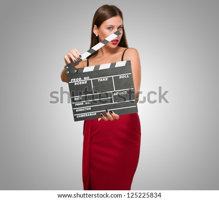 Woman In A Red Dress Holding Clapper Board against a grey background