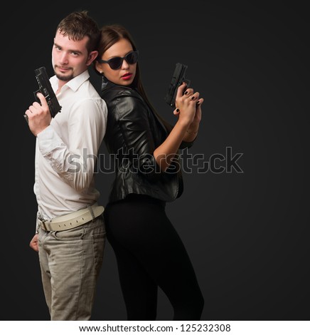 Young Couple Holding Gun against a black background