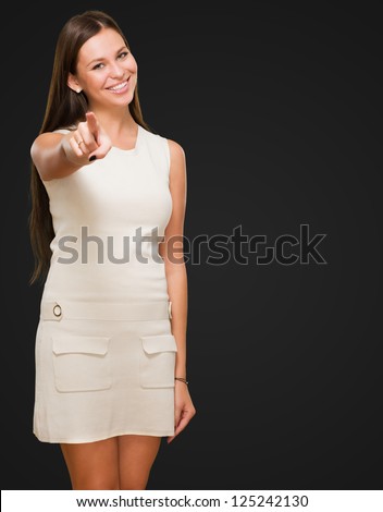 Portrait Of A Happy Young Woman Pointing At You against a black background