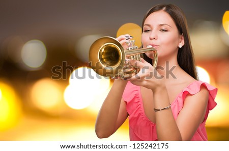Portrait Of A Young Woman Blowing Trumpet against a city by night