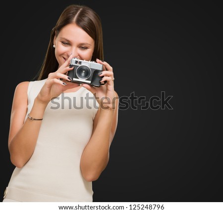 Young Woman Holding Camera against a black background