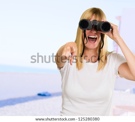 woman looking through binoculars and pointing at the beach