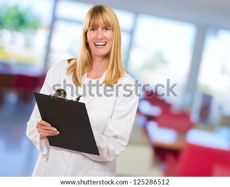Portrait Of Happy Doctor Writing On Clipboard at a waiting room