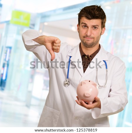 Young Doctor Holding Piggy Bank, Indoor