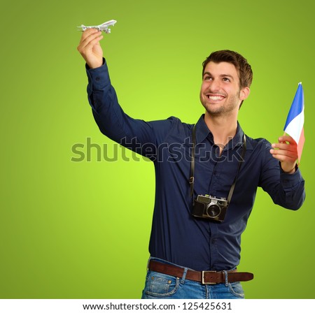 Man holding flag and miniature of airplane on green background - stock photo