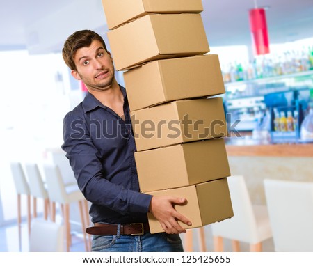 Young Man Holding Stack Of Card boxes In Restaurant