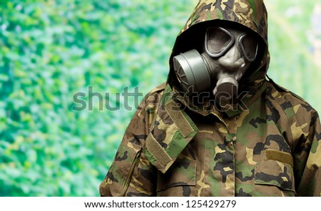 angry soldier wearing a gas mask against a nature background
